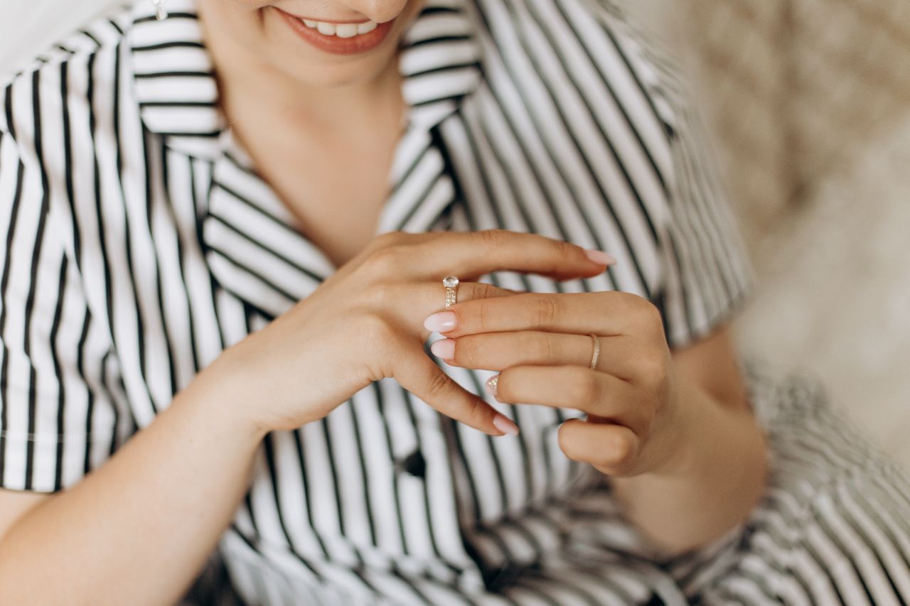 A smiling woman in a striped shirt trying on an engagement ring.